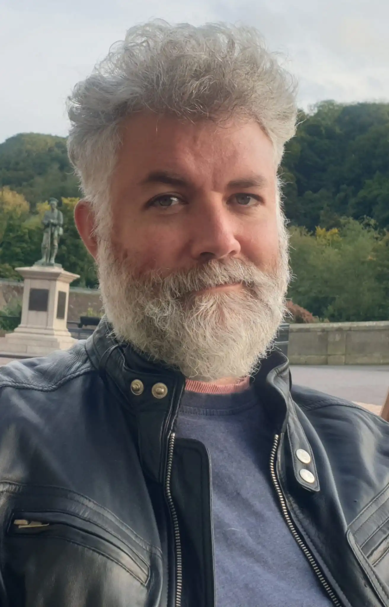 John E. Parman standing in a leather jacket, looking directly at the camera