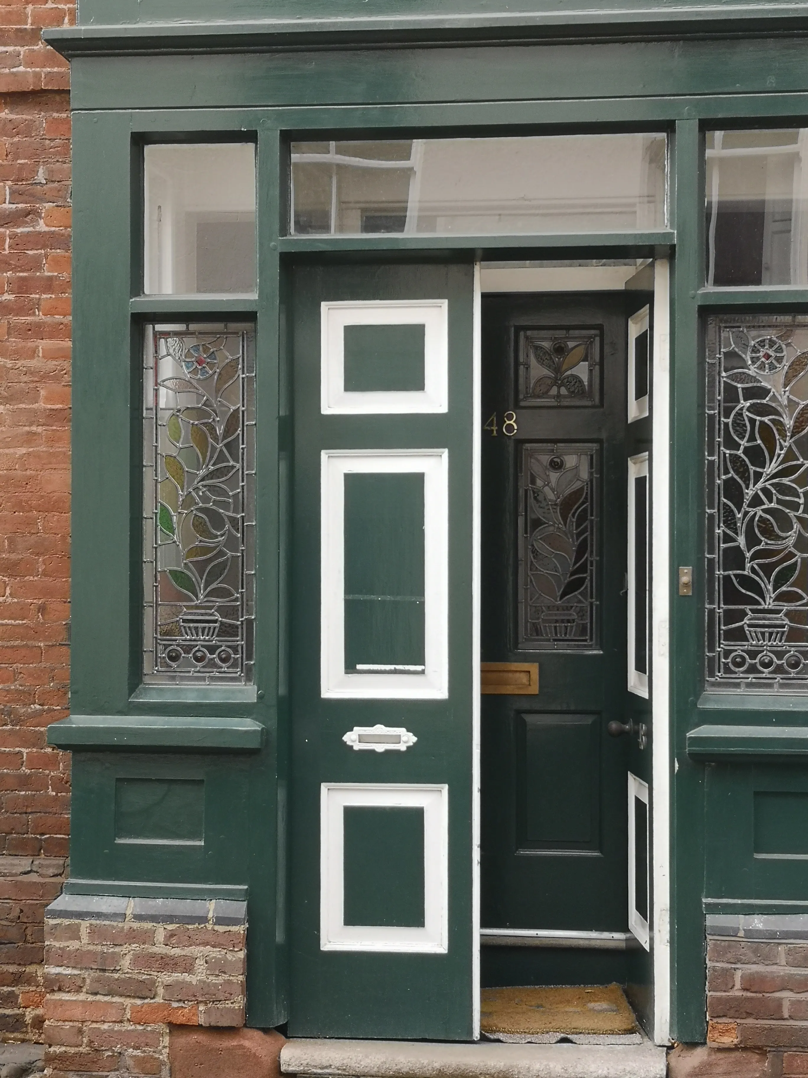 Ornate Victorian-style stained-glass front door on a brick terrace in Herefordshire